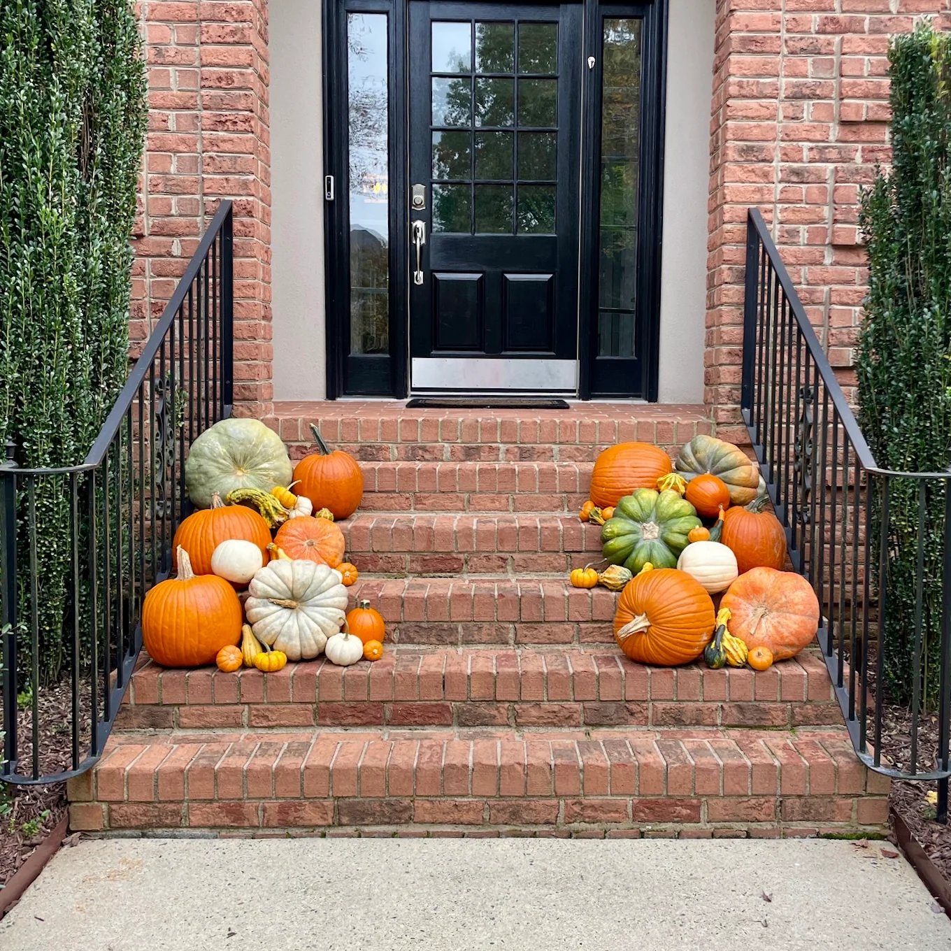 Brick steps styled with a mixed pumpkin and gourd display in cream, orange, and sage