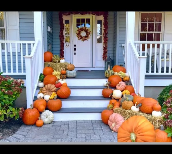 Wide porch steps styled on both sides with pumpkins, gourds, and mums