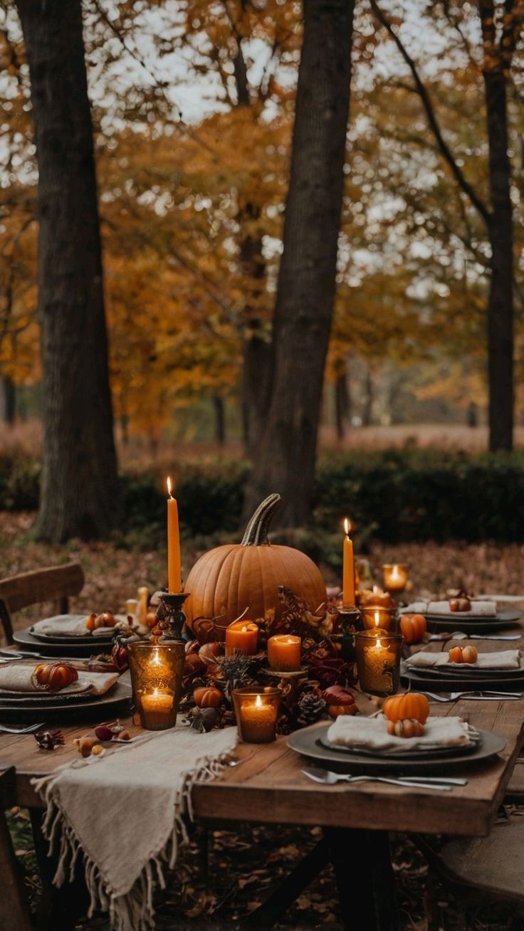 Wooden outdoor table with a pumpkin candle centerpiece surrounded by autumn trees